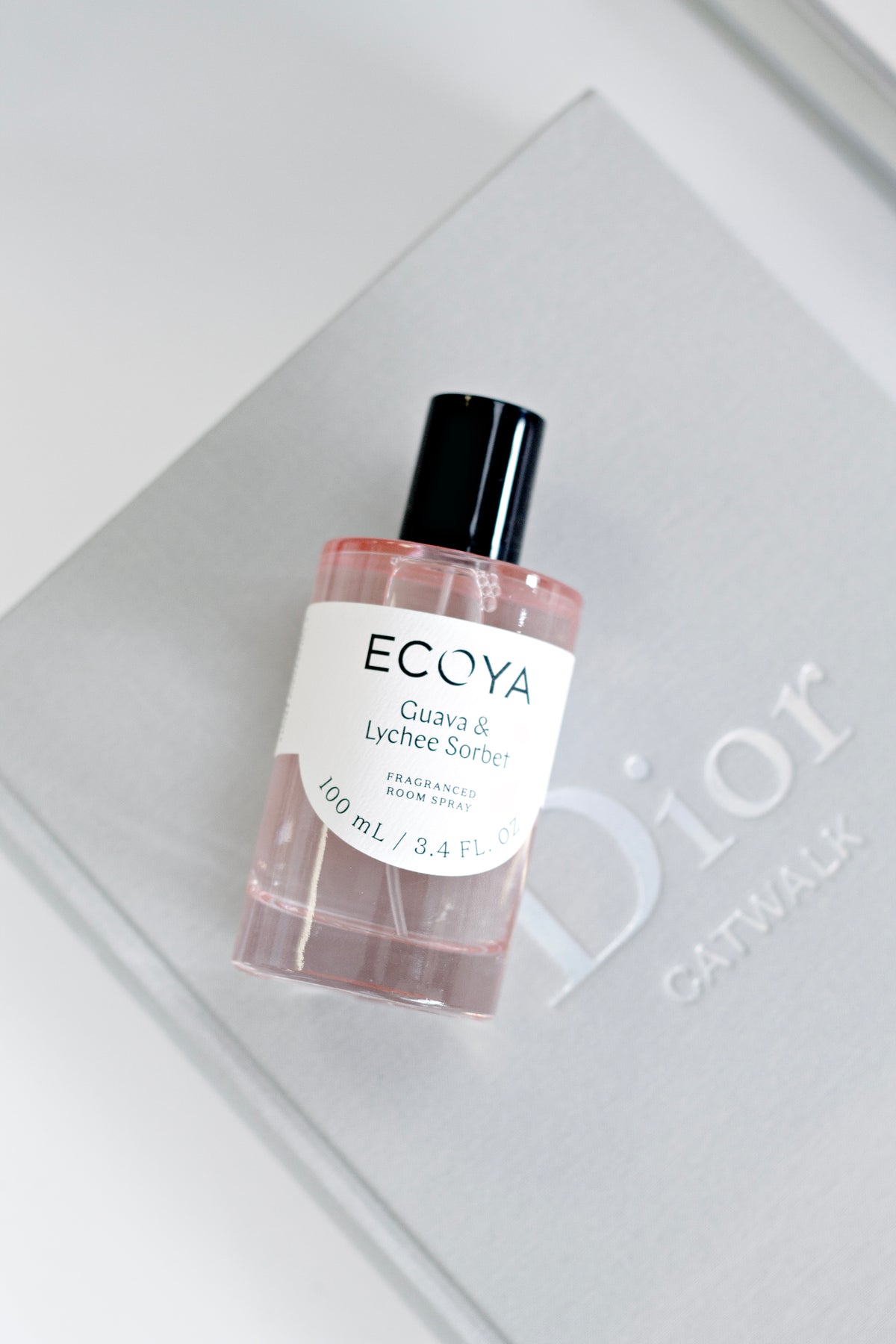 Pink-tinted Ecoya room spray lying on a grey coffee table book