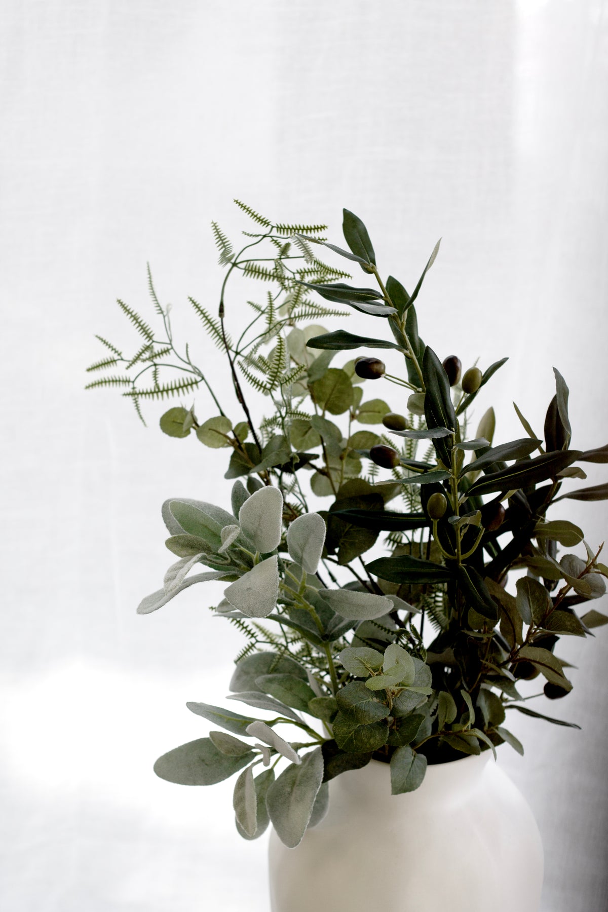 Faux eucalyptus and olive foliage in a white vase