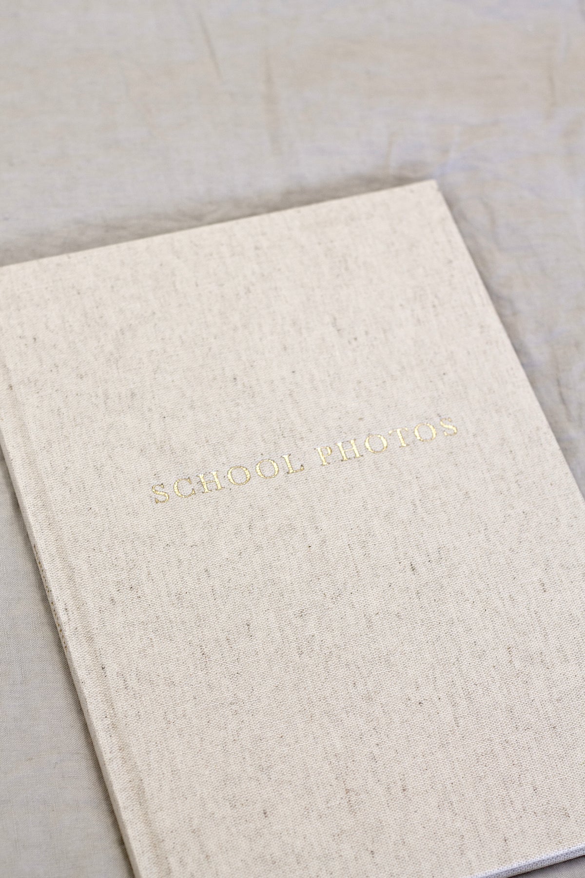 Oatmeal linen School Photos journal lying on a soft neutral throw