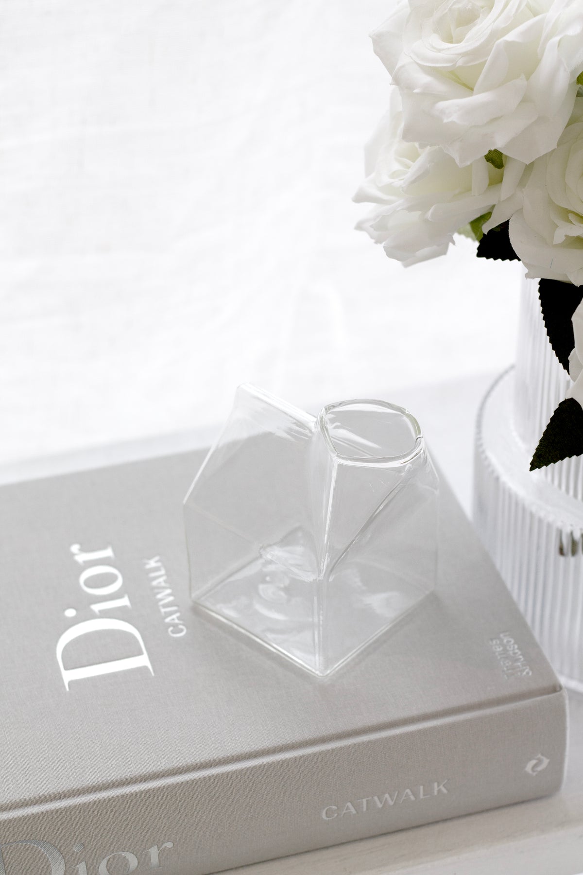Glass milk carton creamer styled on a kitchen bench beside a coffee cup