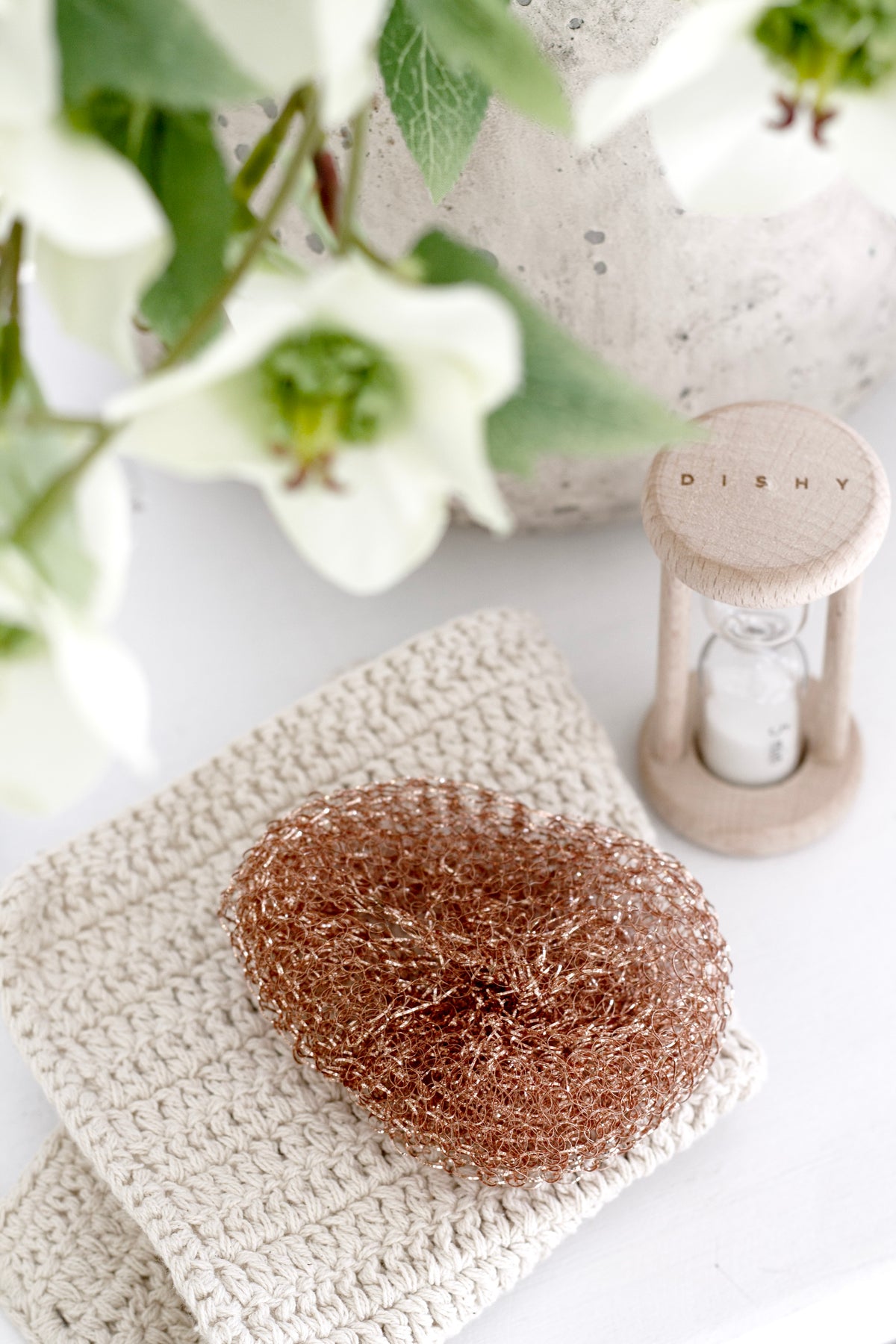 Copper sponge on a knitted cloth beside white flowers
