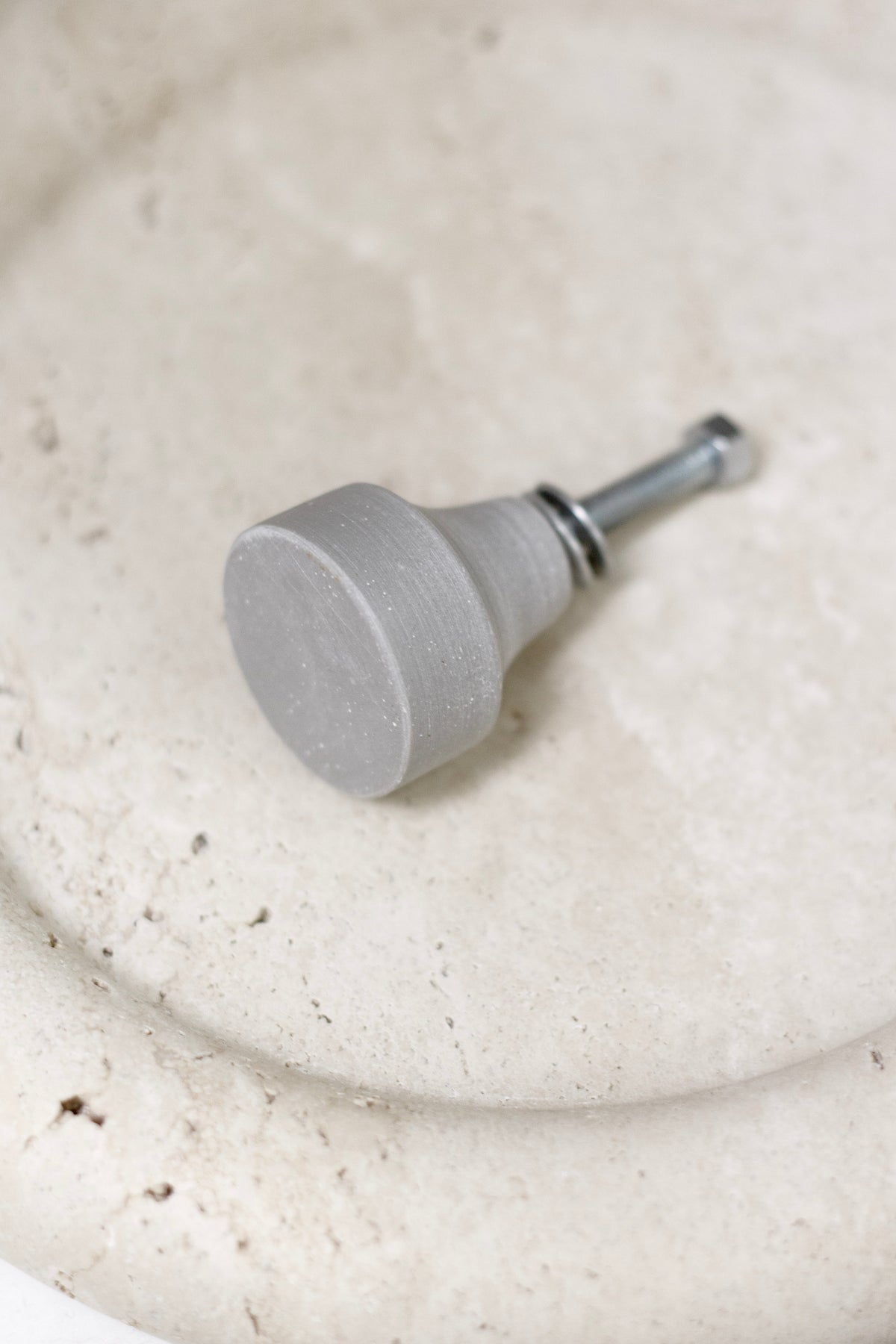 Zakkia concrete cabinet knob resting in a pale concrete dish
