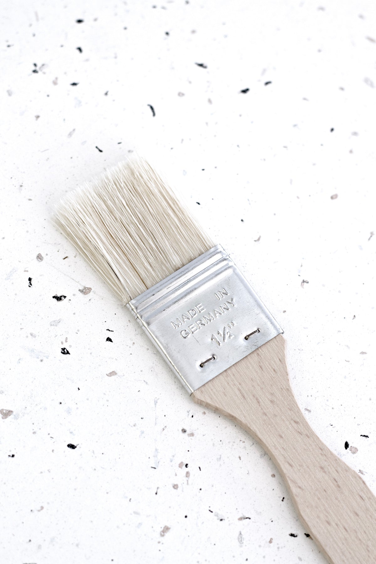 Close view of the pastry brush on a terrazzo bench, showing bristles and ferrule