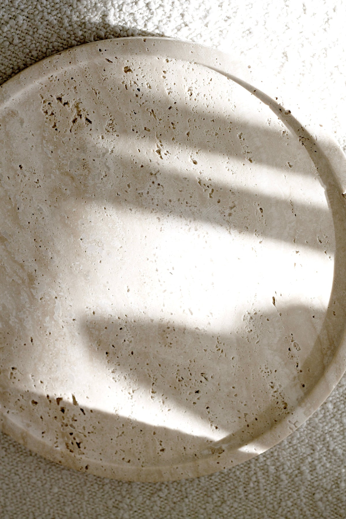 Moon round travertine tray styled with candle and skincare bottles on a neutral surface