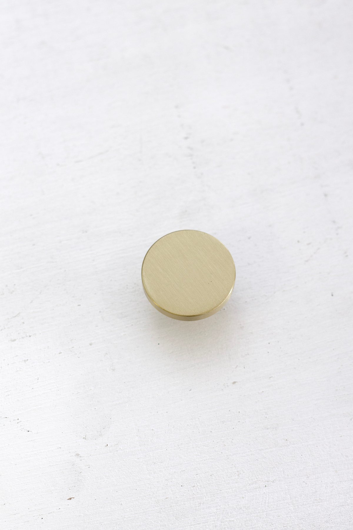 Brushed gold brass hook face-up on a white surface