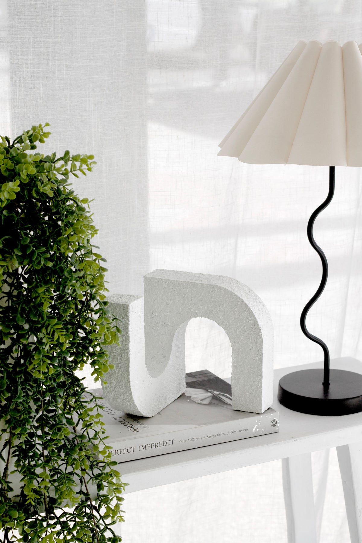 Console scene with the arch ornament, a pleated shade lamp and foliage at the edge