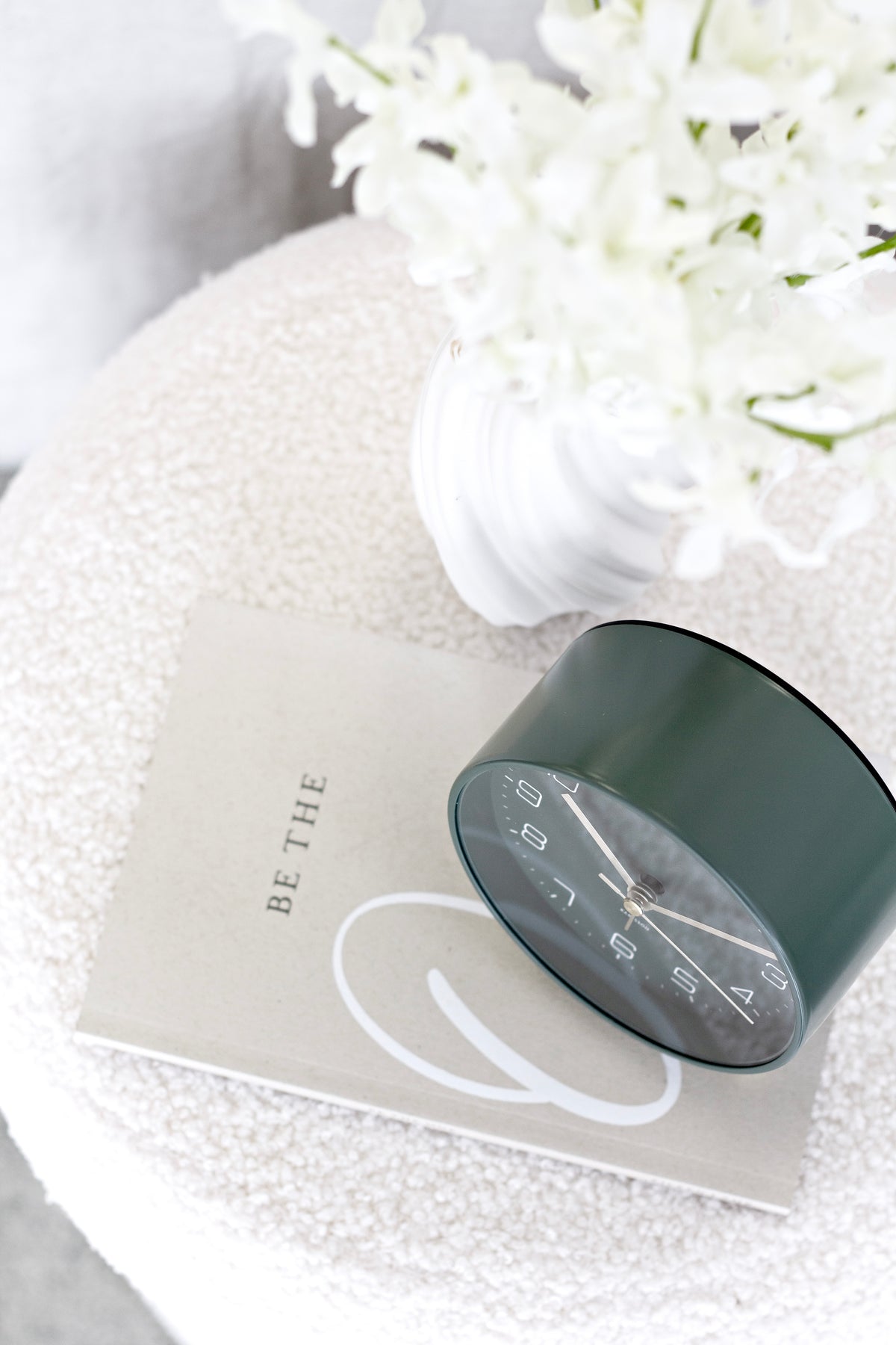 Green Karlsson Lofty alarm clock close up beside white flowers