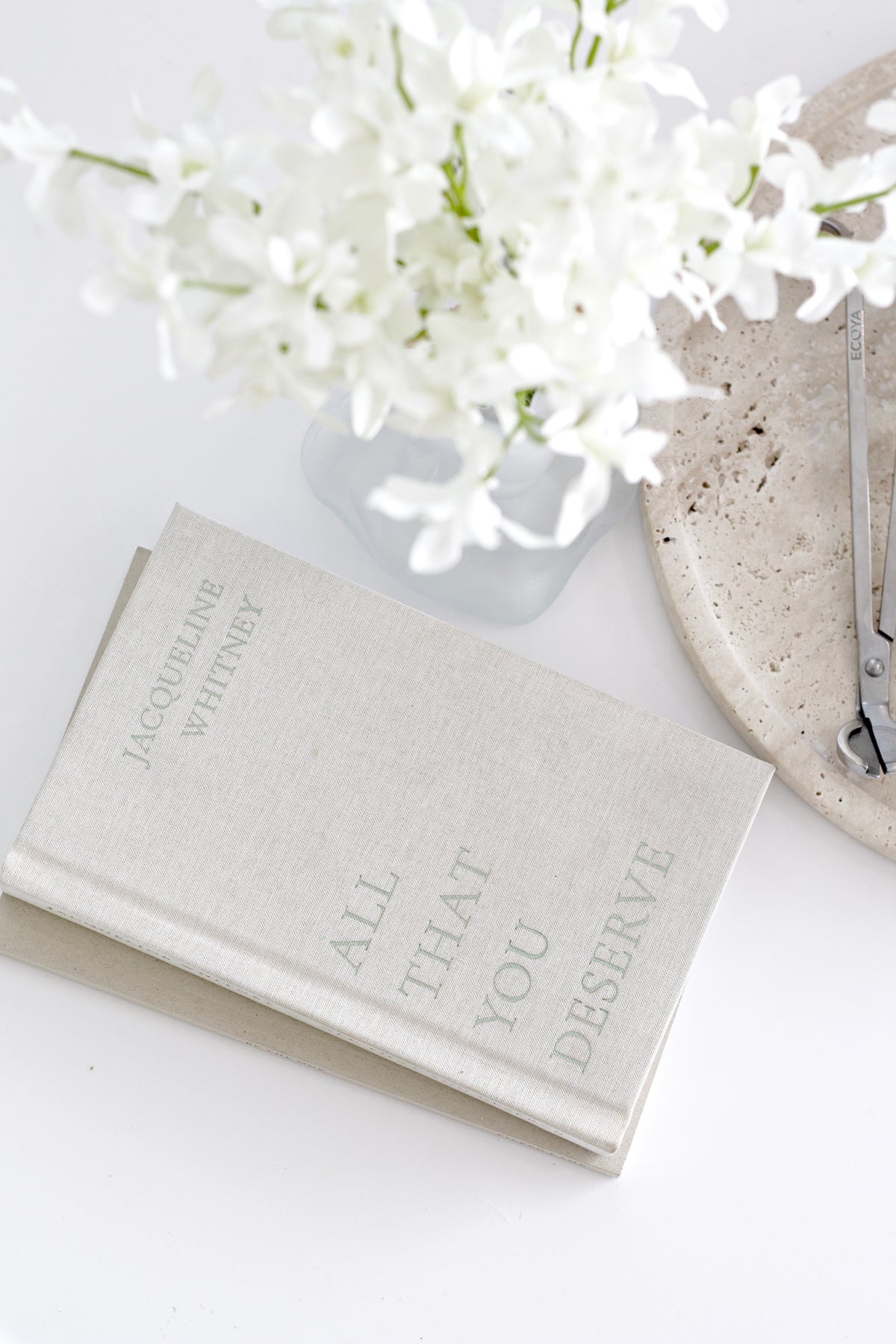 Faux orchids beside a book on a pale surface
