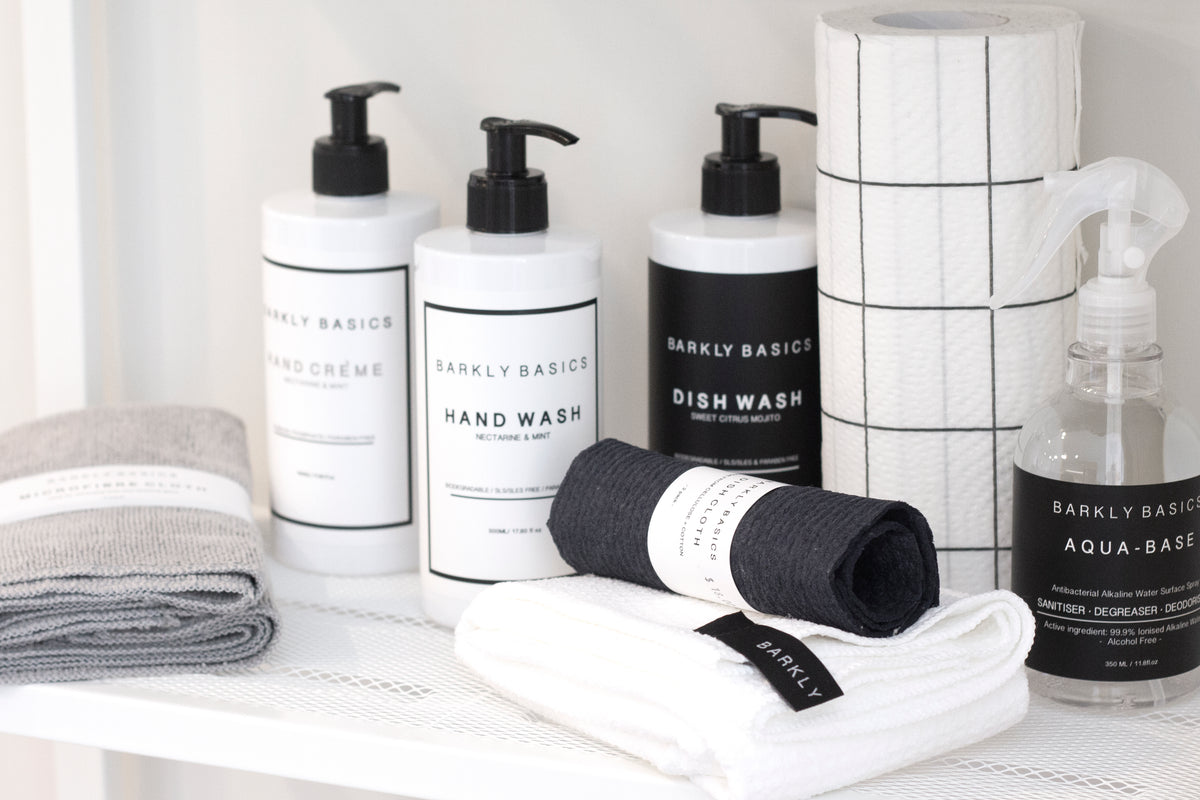 Barkly Basics hand wash, dish wash and hand creme bottles with folded cloths on a white shelf