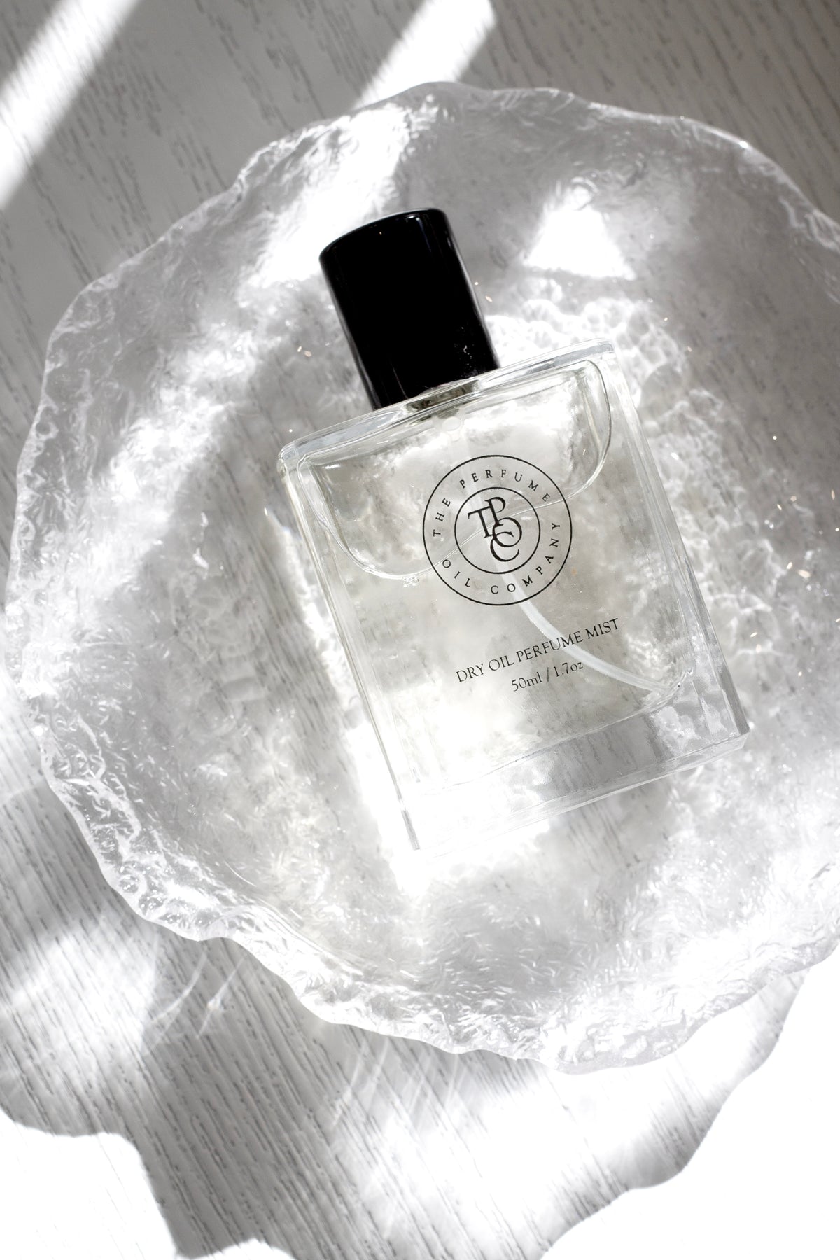 Roll-on perfume oil bottle resting in a rippled clear glass dish