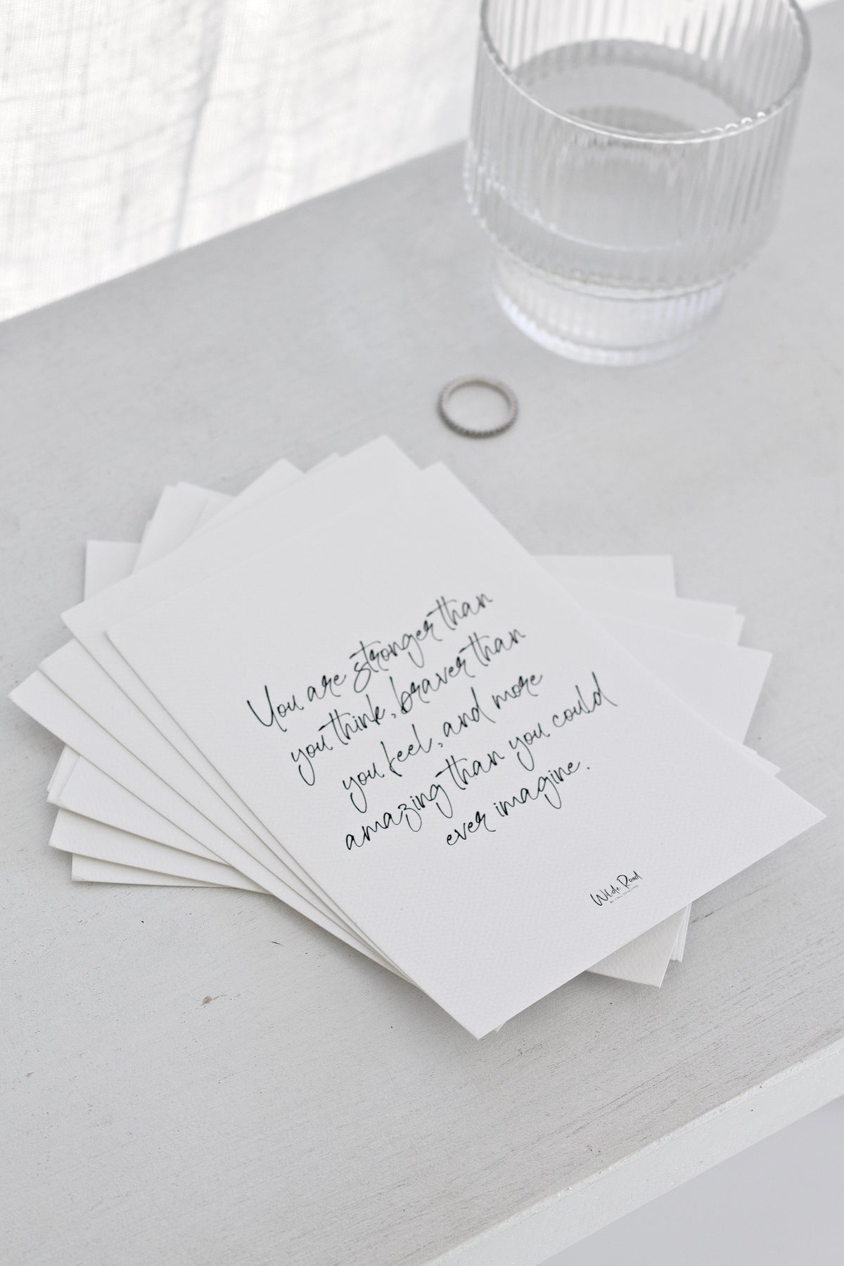 Affirmation cards spread on a white table with a glass tumbler