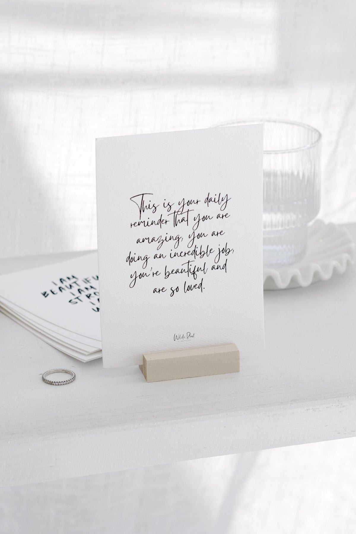 Affirmation card on a wooden stand beside a glass of water
