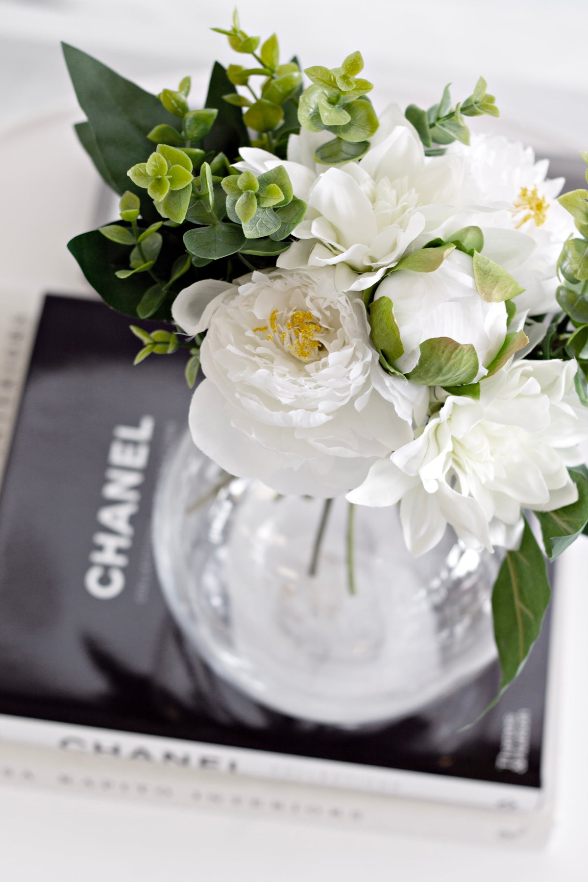 Bouquet in a glass vase on black coffee table books, close view