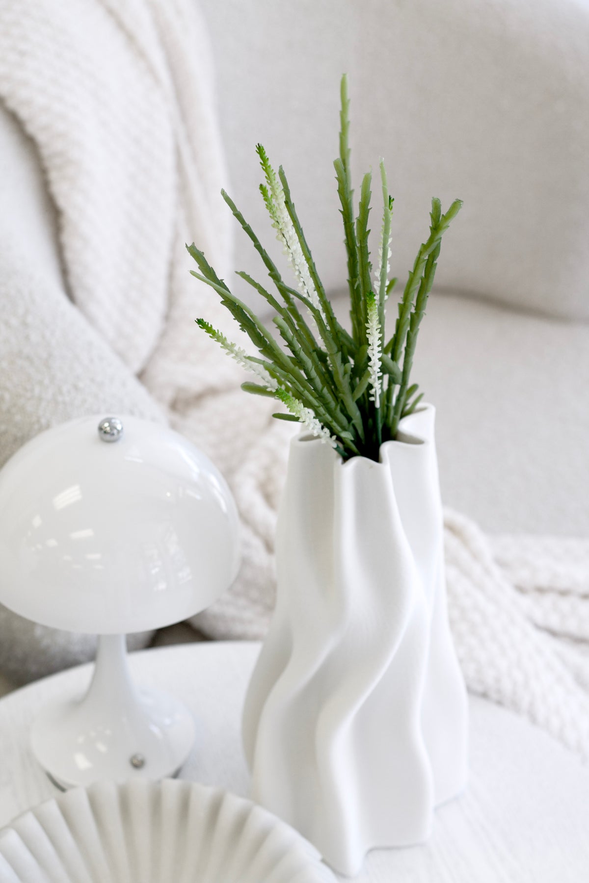 Rhipsalis in a wavy white vase beside a white mushroom lamp
