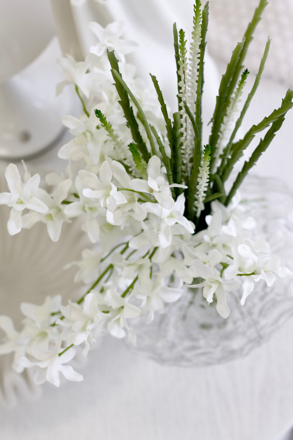Faux orchid bundle in a cut glass vase in soft light