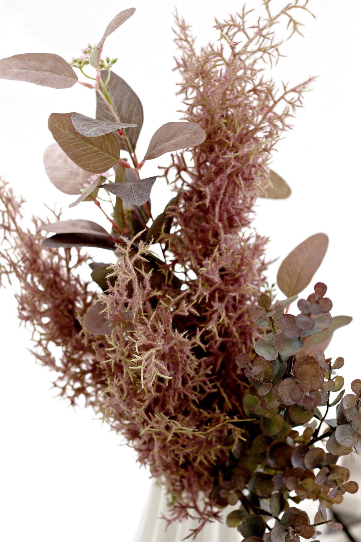 Faux eucalyptus with rust dried foliage in a white vase
