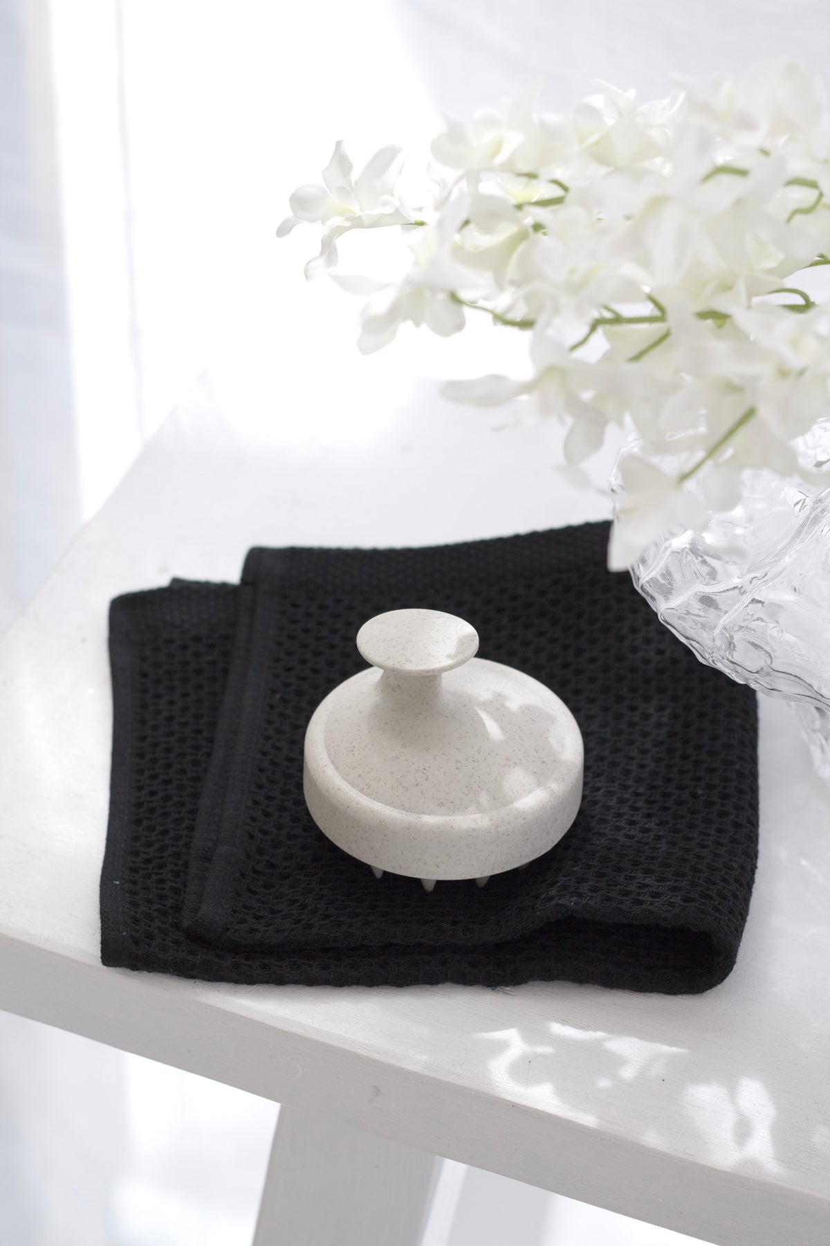 Close view of the black waffle-weave cloth and white brush in window light