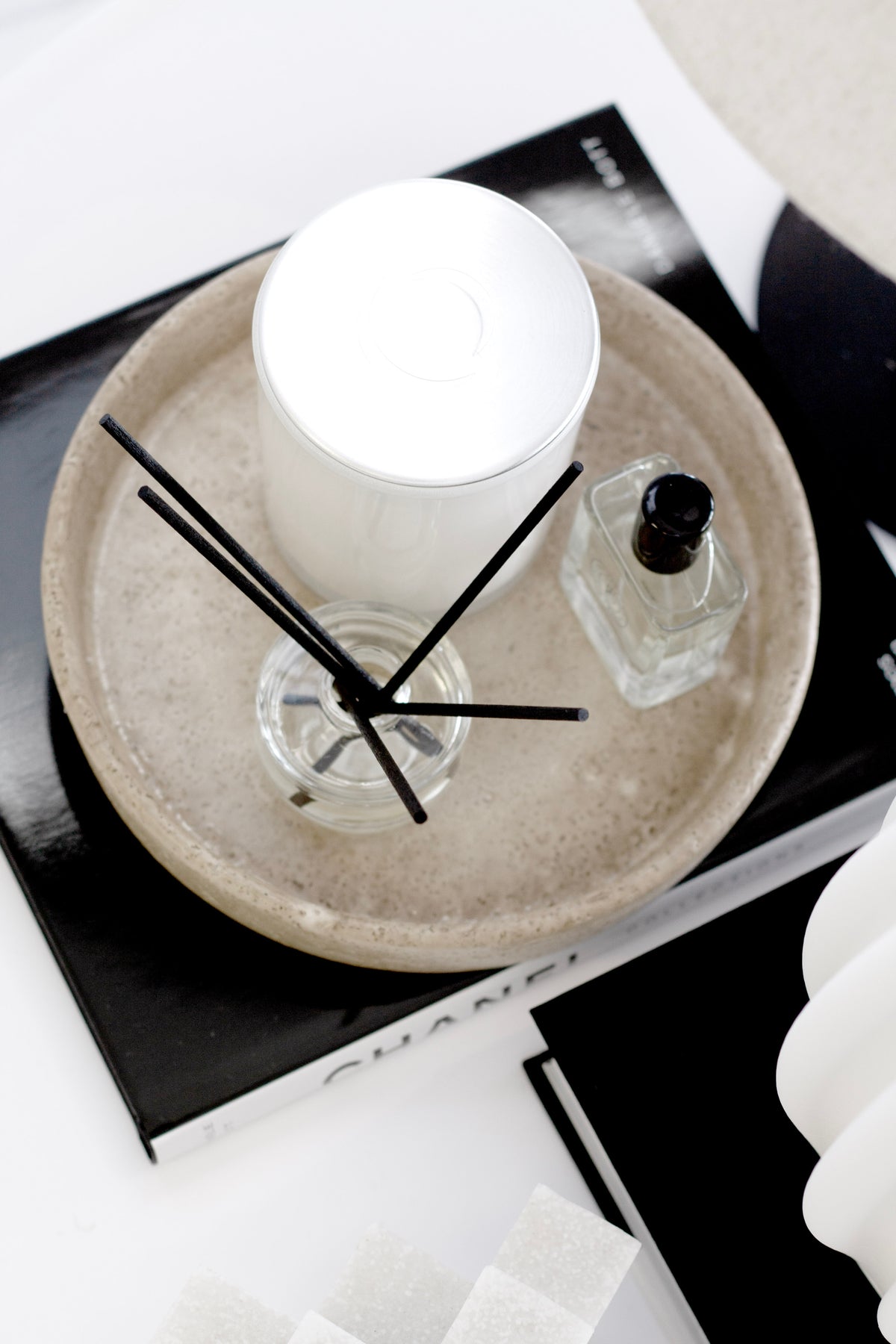 Sahara ceramic tray holding a lit candle and a reed diffuser, on dark coffee table books