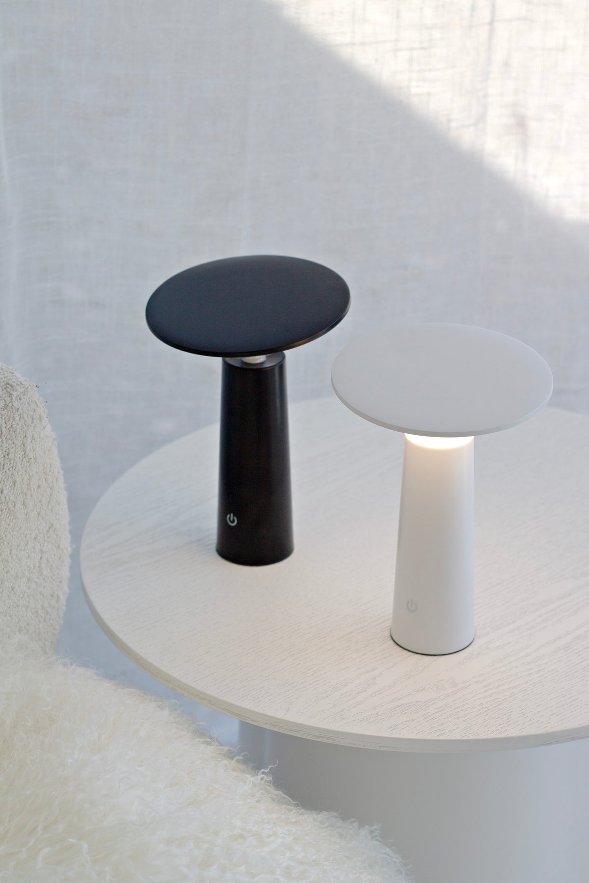 Black and white LED Tilt lamps side by side on a round table