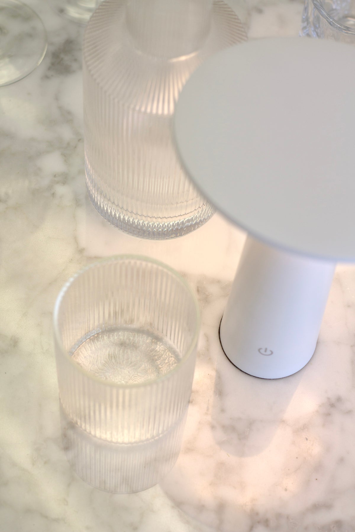Close view of the white LED Tilt lamp shade with ribbed glassware behind