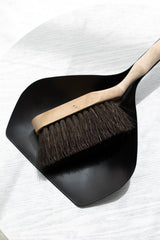 Black dustpan with wooden handle on a white background