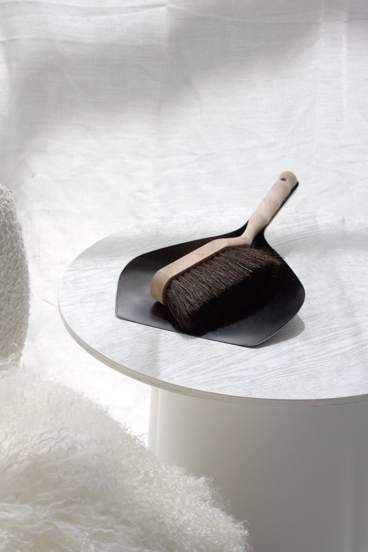 Dustpan and brush set on a white surface with a soft white background