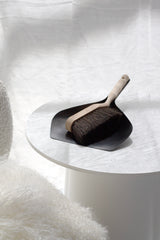 Dustpan and brush set on a white surface with a soft white background
