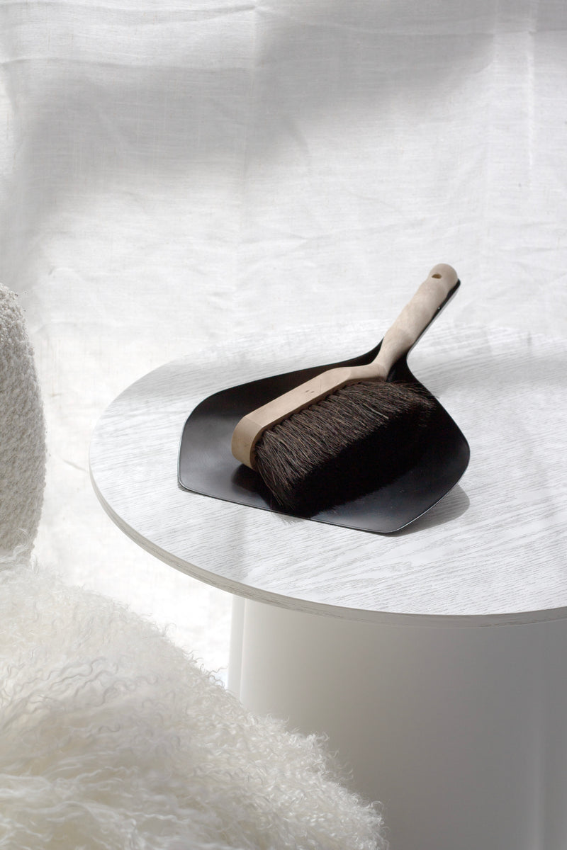 Dustpan and brush set on a white surface with a soft white background