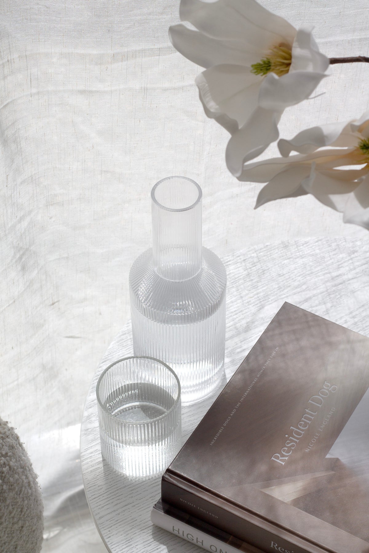 Amalfi decanter and glass beside white blooms and a stack of books