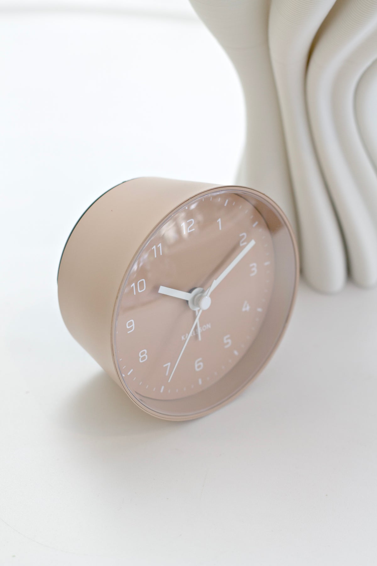 Sand Brown Cone alarm clock in side profile beside a white wavy vase