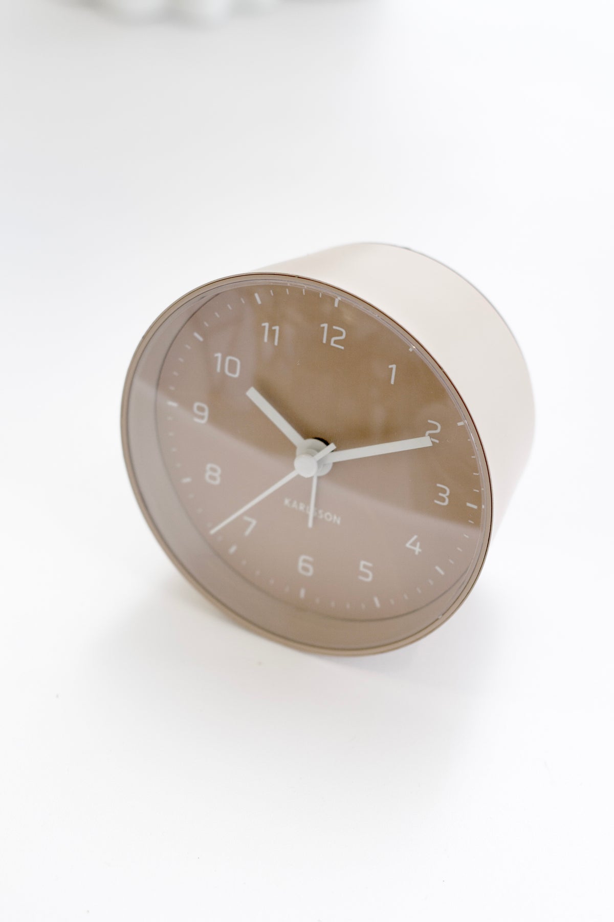 Sand Brown Karlsson Cone clock on a white surface in soft light