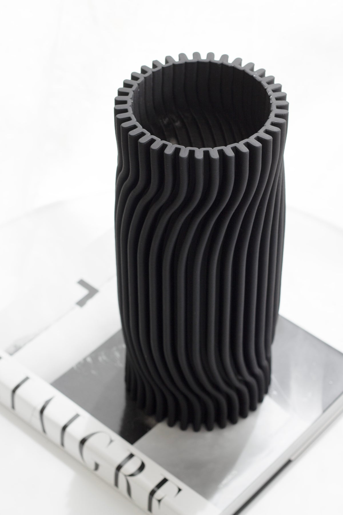 Black Rocco ribbed vase standing on a hardback book on a white surface