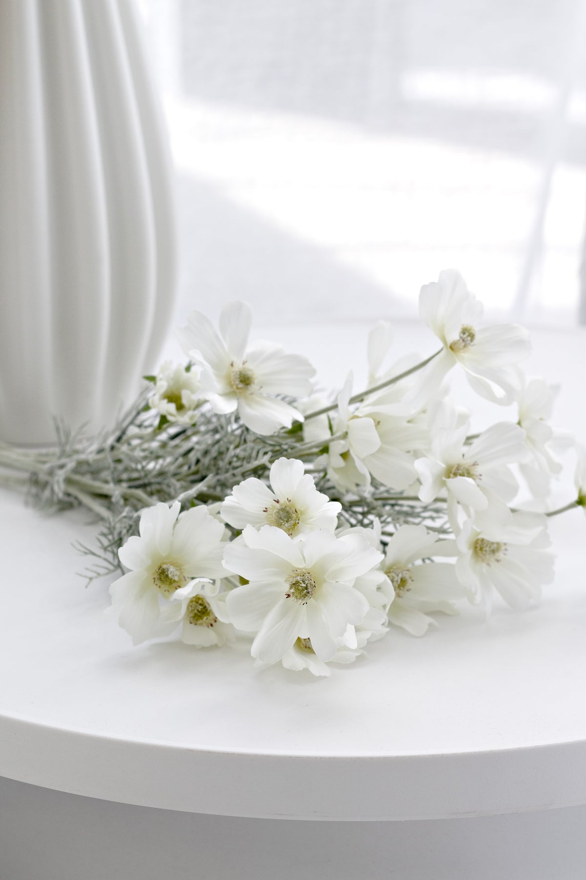 White faux cosmos laid on a round white table