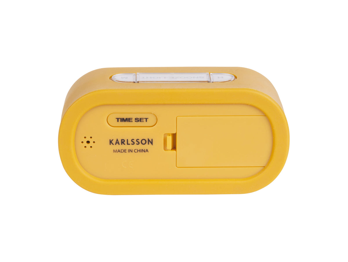 Back of the Karlsson Gummy Digital Alarm Clock in ochre yellow showing the time set button and battery compartment