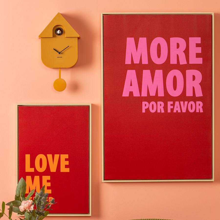 Karlsson Modern Cuckoo Clock in Bright Yellow hanging beside red typographic posters