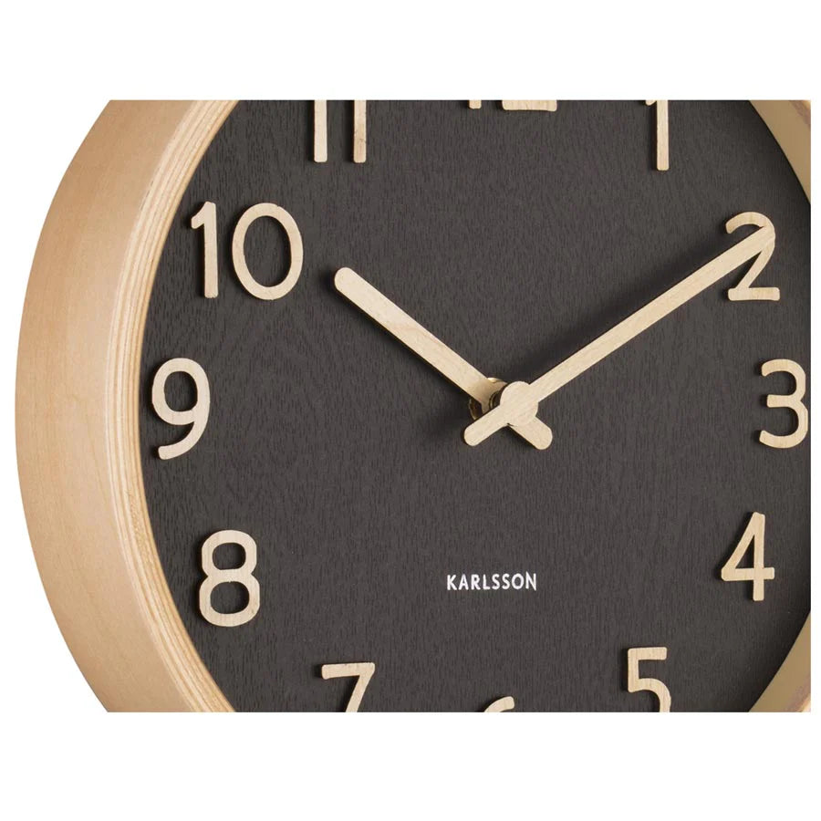 Close-up of the black Karlsson Pure Wall Clock with basswood frame and light hands