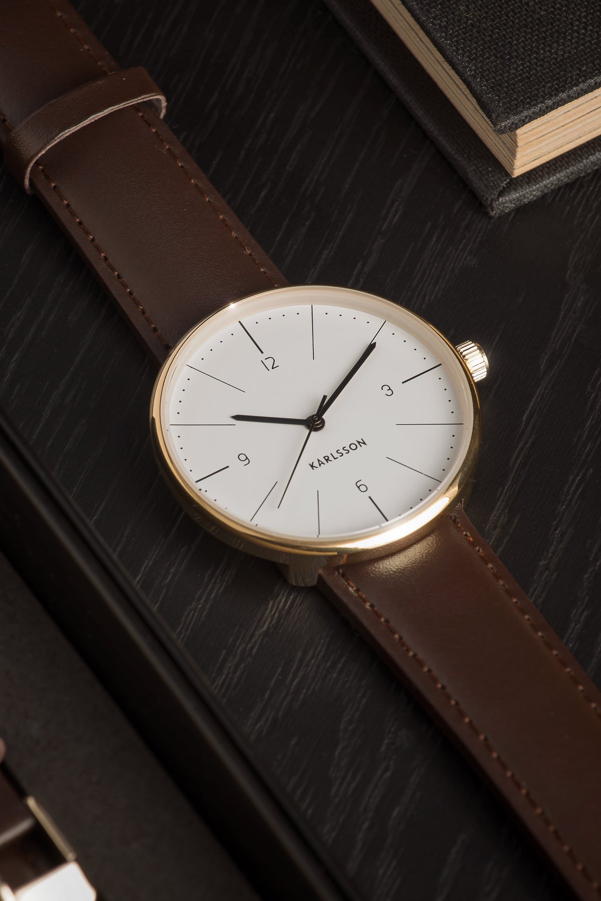 Close up of the Karlsson Normann white dial and gold case on a dark wood surface