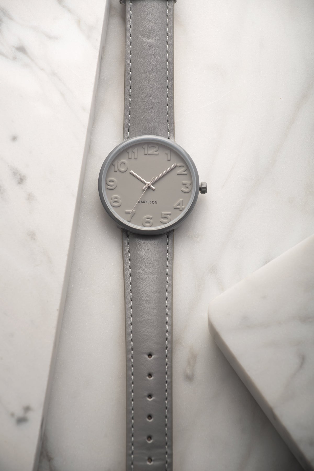 Karlsson Ms Grey watch lying on white marble with the strap extended