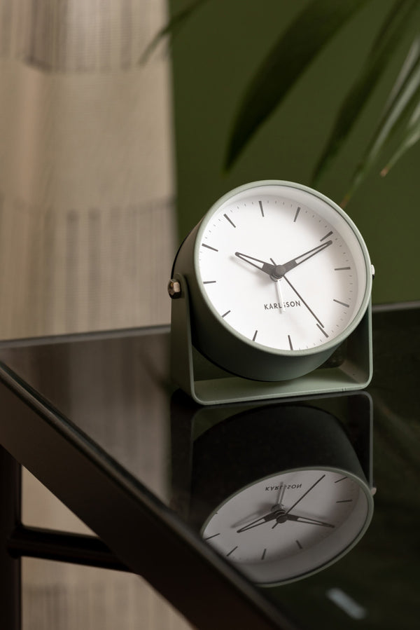 Greyed Jade Karlsson Calm alarm clock on a black glass side table beside a plant