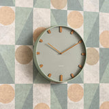 Grayed jade Grace wall clock styled on a patterned wall
