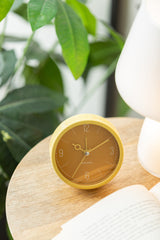 Ochre yellow Monocle alarm clock styled on a shelf with greenery