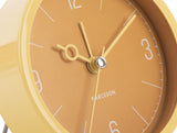 Close up of the ochre yellow Monocle clock face and glass lens