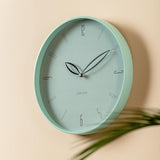Misty blue Petals wall clock styled on a wall with greenery