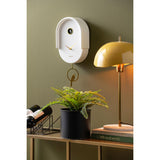 White Tweet pendulum clock styled on a wall with greenery