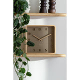 Soft brown Nervadura wooden square wall clock styled on a shelf