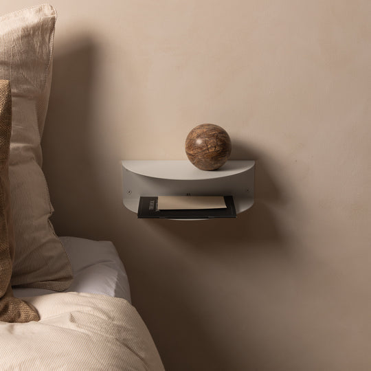 White FOLD Bedside Table Mini beside a bed holding a stone ball and books