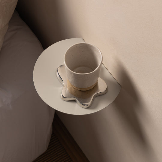 Close-up of a white FOLD Round Shelf holding a cup on a coaster