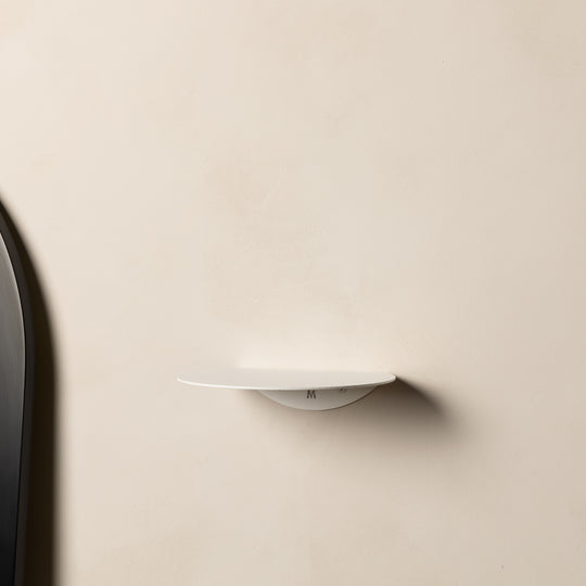 Empty white FOLD Round Shelf on a cream plaster wall
