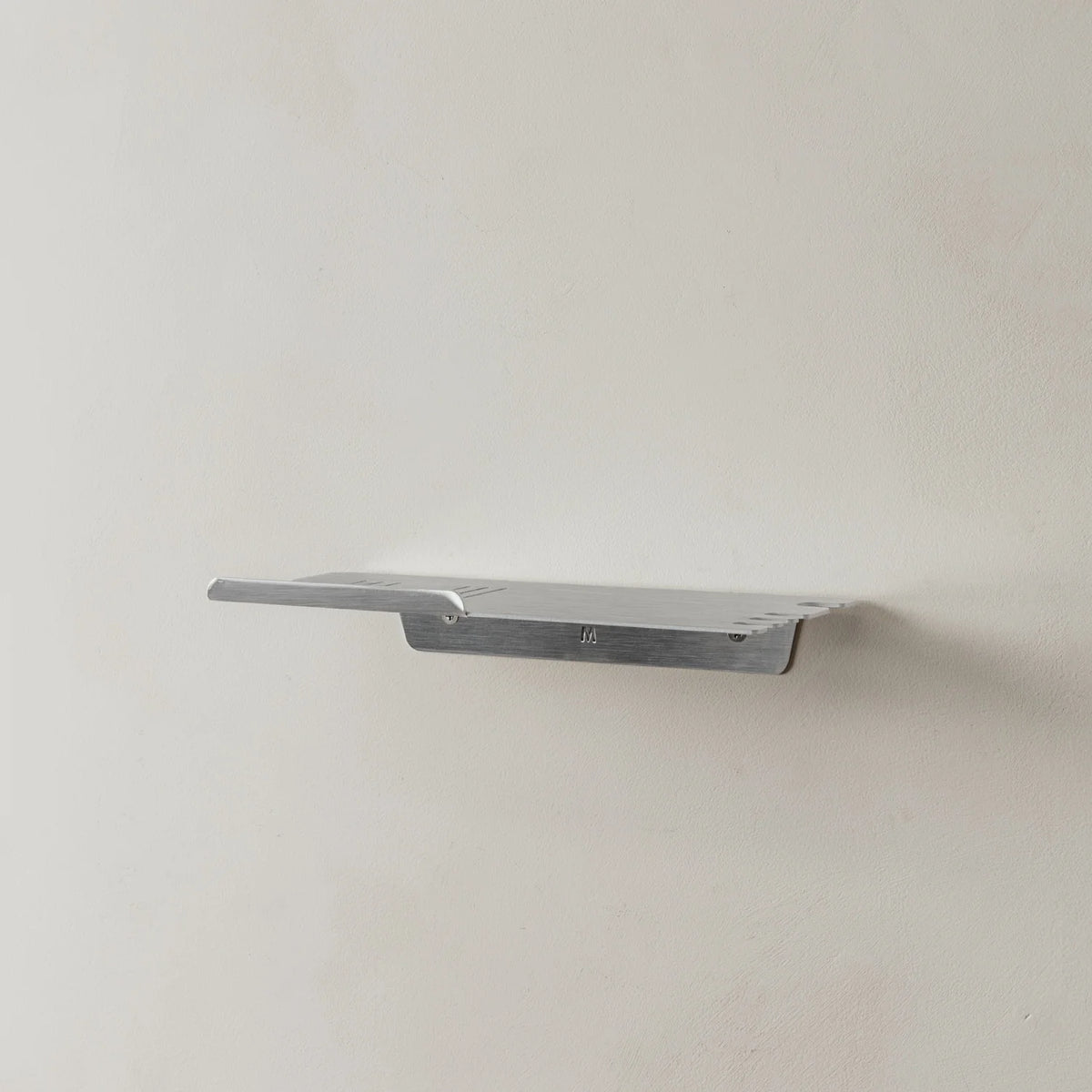 Empty brushed aluminium FOLD shower shelf on a grey wall