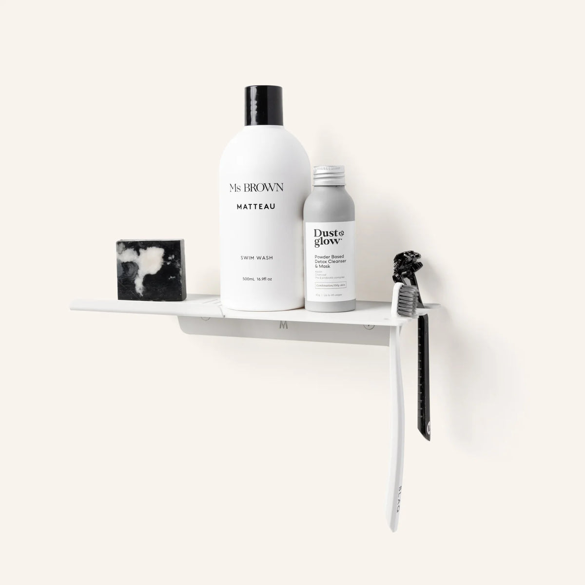 White FOLD shower shelf with bottles and a toothbrush on a cream wall